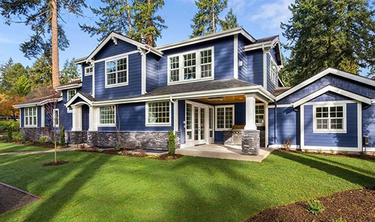 A blue house with white trim and stone pillars.